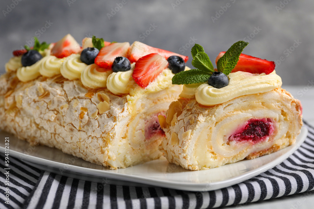 Tasty meringue roll with jam, cream, strawberry, blueberry and mint on plate, closeup Tasty meringue roll with jam, cream, strawberry, blueberry and mint on plate, closeup
