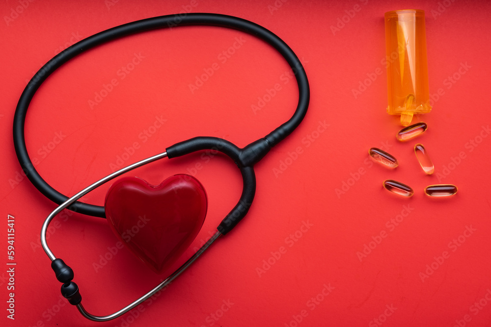 medical stethoscope, red heart and pills on a red background. View from above. Space for text medical stethoscope, red heart and pills on a red background. View from above. Space for text