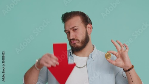 Upset lebanese man showing red arrow pointing down downgrade, unsuccessful business fall of cryptocurrency stock market investment, mining bitcoins BTC money exchange rate bankruptcy fail. Arabian guy photo