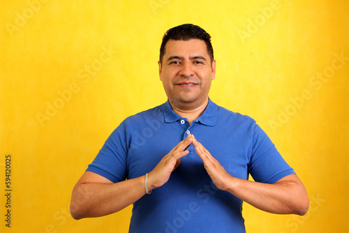Dark-haired Latino adult man uses sign language typical of deaf people to establish a channel of communication with his social environment 