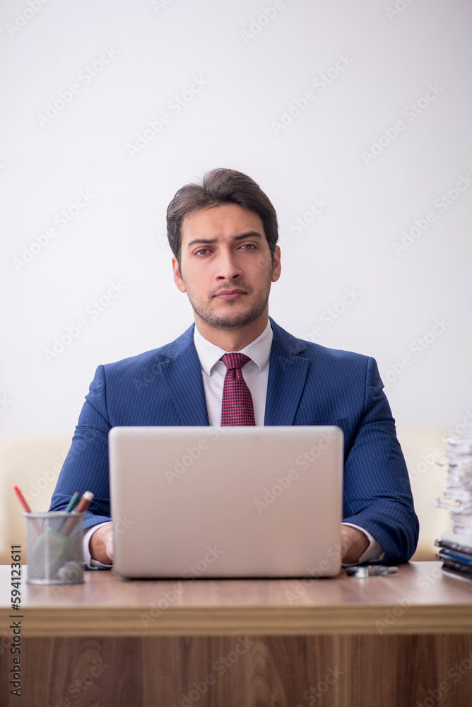 Young male employee unhappy with excessive work in the office Young male employee unhappy with excessive work in the office