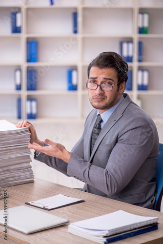 Young male employee and too much work at workplace