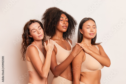Three representatives of different races pose in the studio in underwear and with their eyes closed, holding each other's shoulders, racial harmony concept, copy space, high quality photo © South House Studio