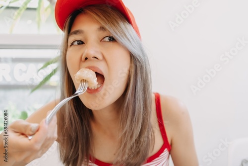 Funny asian cute girl in red eating fried dough dessert.