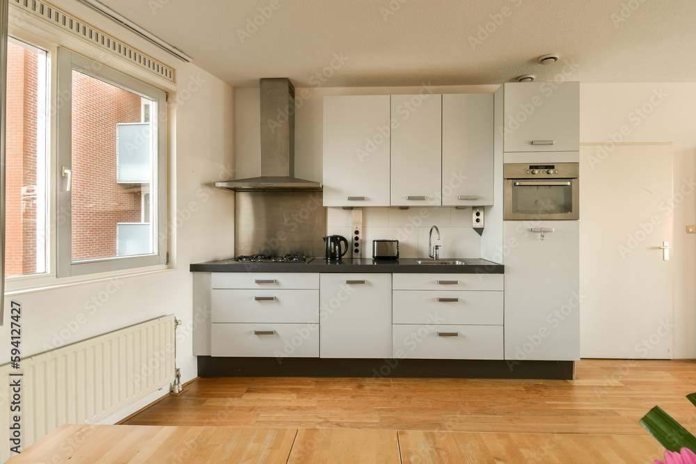 a kitchen with white cabinets and wood flooring in the middle of the room, looking out to the outside a kitchen with white cabinets and wood flooring in the middle of the room, looking out to the outside