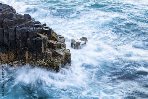 Fototapeta Naklejka Na Ścianę i Meble -  Waves breaking on rocks - long exposure photo of basalt columns on the coast
