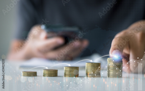 Hand touching coins stacking with infographic arrow jump step for growing business, saving, investment, business investment profit and dividend saving growth concept.