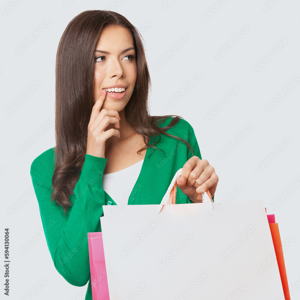 Square image of young asian caucasian woman in green casual cloth wear, sweater hold shopping bags, isolated on light grey gray background. Brunette girl. Sales, rebates, discounts deal offers ad. Square image of young asian caucasian woman in green casual cloth wear, sweater hold shopping bags, isolated on light grey gray background. Brunette girl. Sales, rebates, discounts deal offers ad.