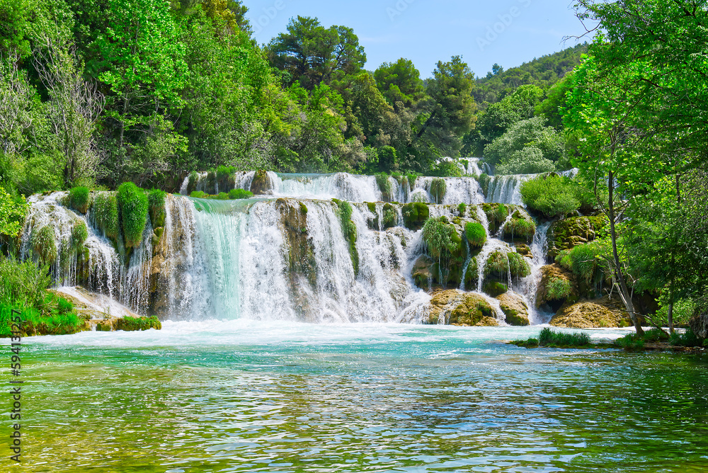 Naklejka premium Beautiful Waterfall background in sunny summer day. Beautiful Waterfall In Krka National Park - Croatia, Europe. Krka river waterfalls in the Krka National Park