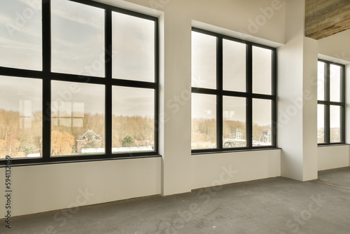 an empty room with large windows and no one person standing in the window looking out to the city outside 
