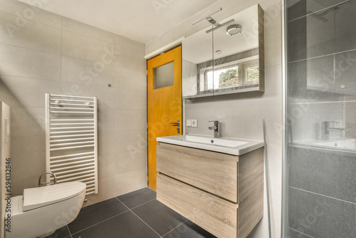 a modern bathroom with grey tiles and white fixtures on the walls, along with a wooden cabinetd toilet in the shower stall is