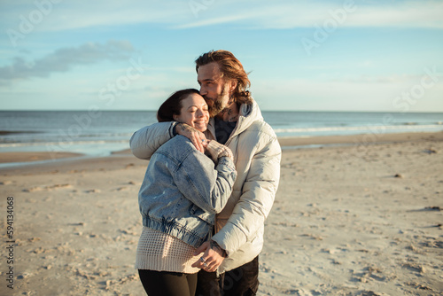 Young adult couple walking on a beach during cold weather