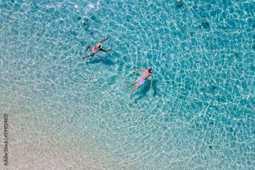 drone view at a men and woman swimming in the blue turqouse colored ocean of Koh Kradan island © Chirapriya