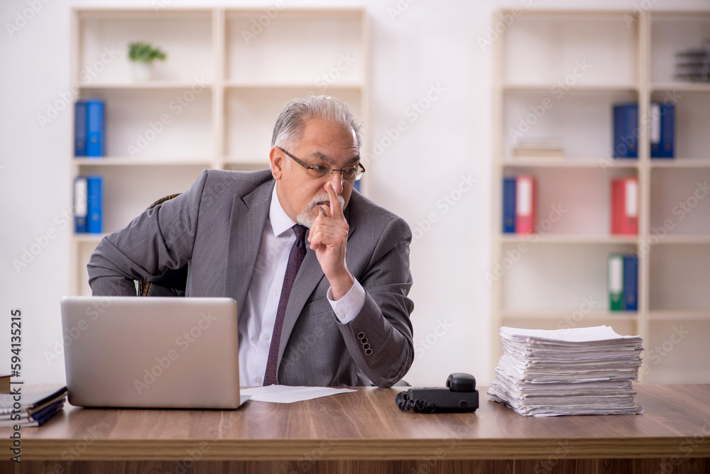 Old male employee working in the office Old male employee working in the office