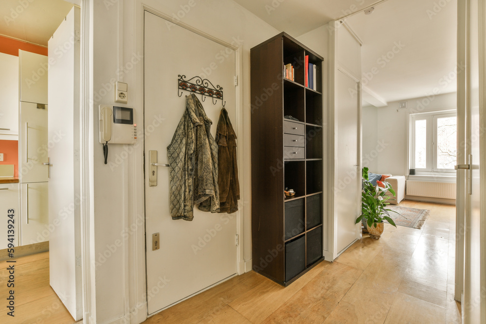 the inside of a house with wood floors and white walls, there is a coat rack hanging on the door the inside of a house with wood floors and white walls, there is a coat rack hanging on the door