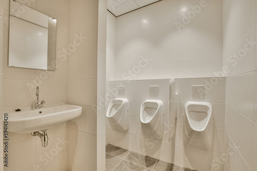 a bathroom with two urves on the wall and a sink in the other part of the room is white