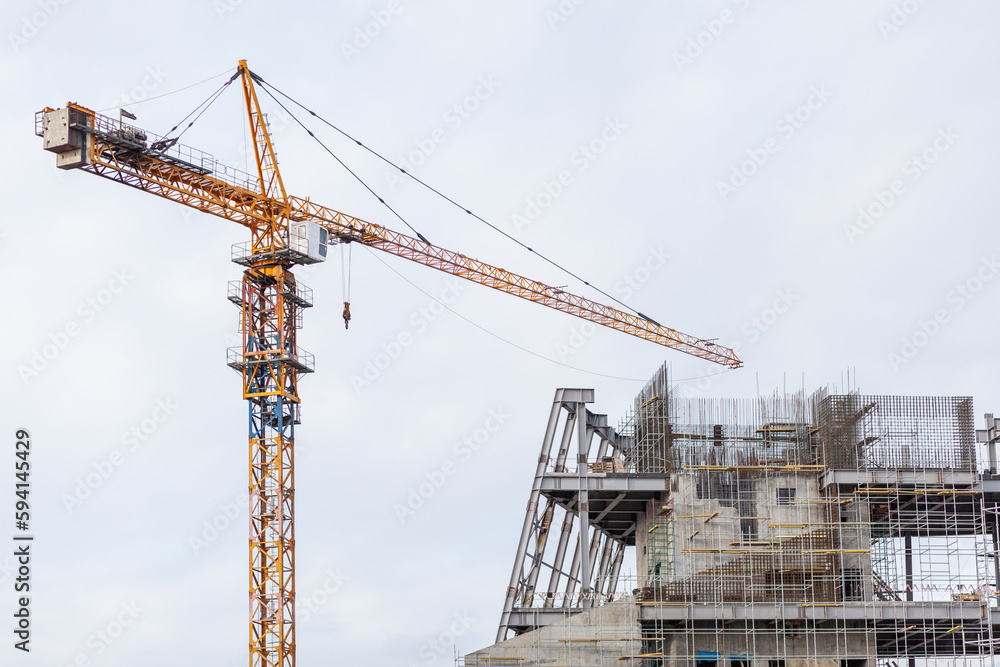 Construction of a large concrete building. Construction crane on the background of the sky. Construction site. 