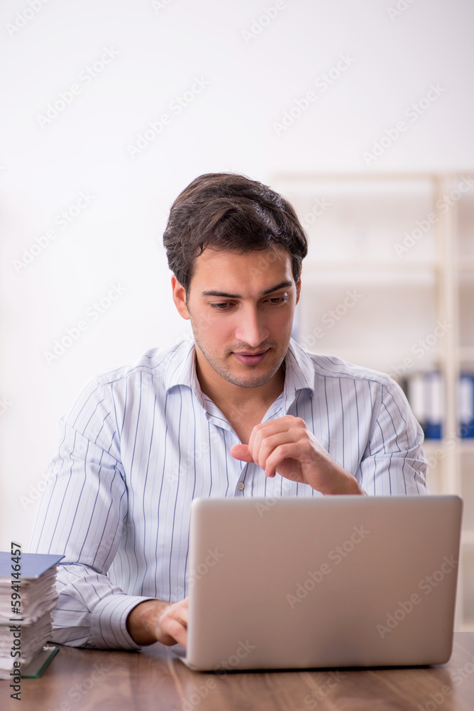 Young male employee and too much work in the office Young male employee and too much work in the office