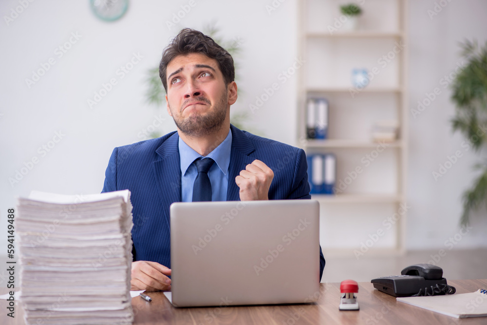 Young male employee and too much work in the office Young male employee and too much work in the office