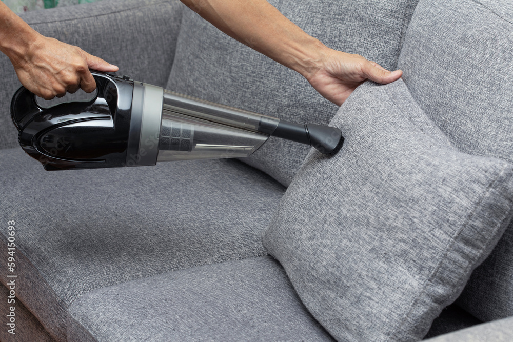 Employee cleaning sofa with vacuum cleaner