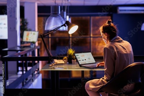 Businesswoman sitting at desk table in business office, analyzing company strategy planning investment plan to increase profit. Entrepreneur working late at night marketing graphs report