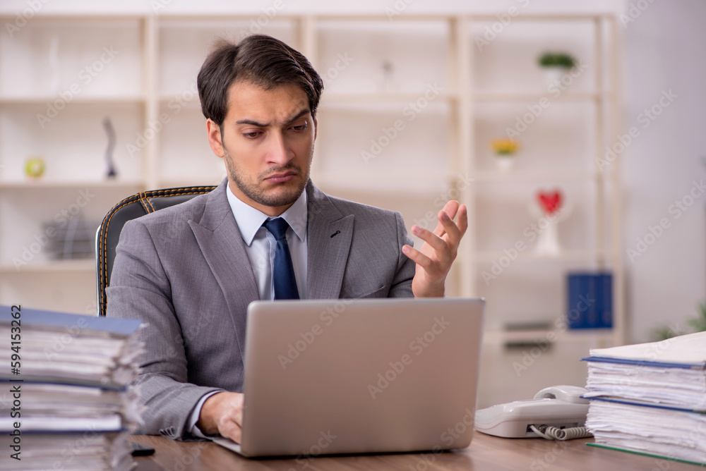 Young male employee and too much work in the office Young male employee and too much work in the office