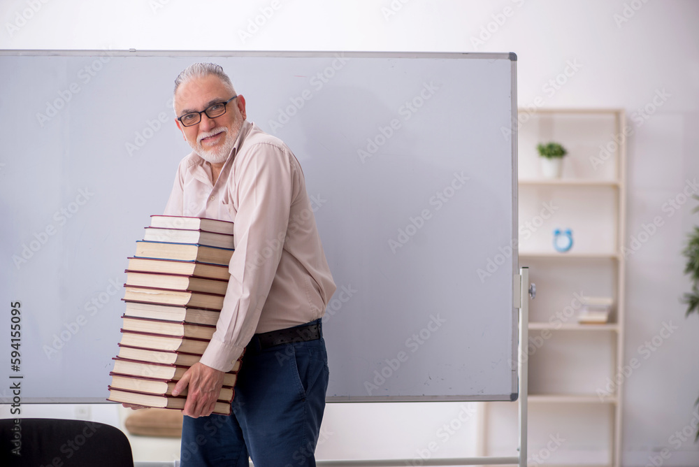 Fototapeta premium Old male teacher sitting in the classroom