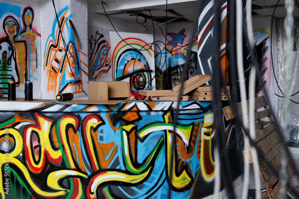 Obraz premium Graffiti on neglected walls looking grunge and artistic, showcasing the talent of the local spray paint artists. Empty old abandoned warehouse filled with garbage and debris, damaged place.