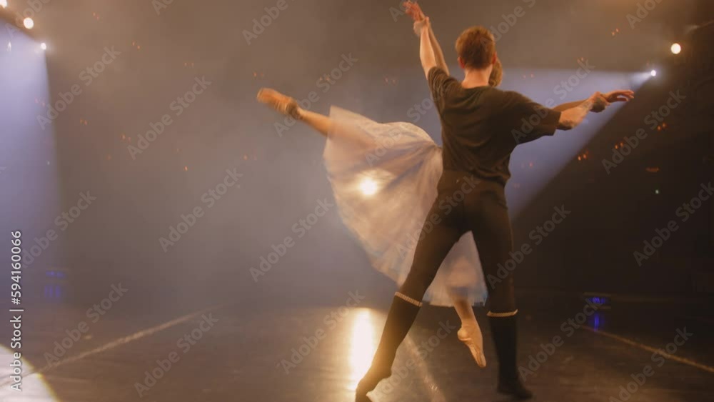 Ballet dancers practice ballet movements and rehearse choreography on classic theater stage illuminated by spotlight. Man and woman prepare theatrical dance performance. Art of classical ballet dance. Ballet dancers practice ballet movements and rehearse choreography on classic theater stage illuminated by spotlight. Man and woman prepare theatrical dance performance. Art of classical ballet dance.