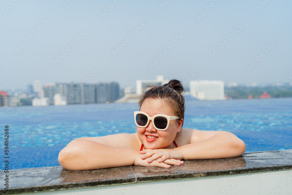 Overweight young asian woman wearing swimsuit relaxing in the pool Happy plus size woman cheery funny Vacation Traveling in summer.