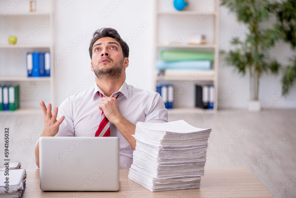 Young male employee and too much work in the office Young male employee and too much work in the office