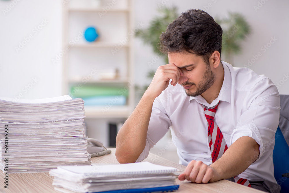 Young male employee and too much work in the office Young male employee and too much work in the office