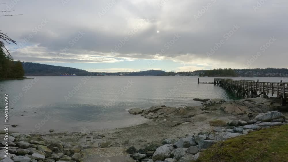 Wooden Quay on a rocky beach in Indian Arm, Vancouver, British Columbia, Canada. Belcarra Pier, West Coast of Pacific Ocean. Spring Season Sunny Cloudy Evening. Slow Motion