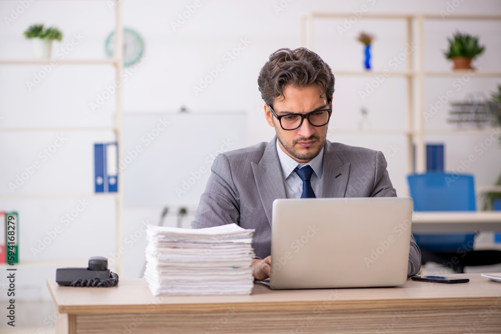 Young male employee sitting at workplace Young male employee sitting at workplace