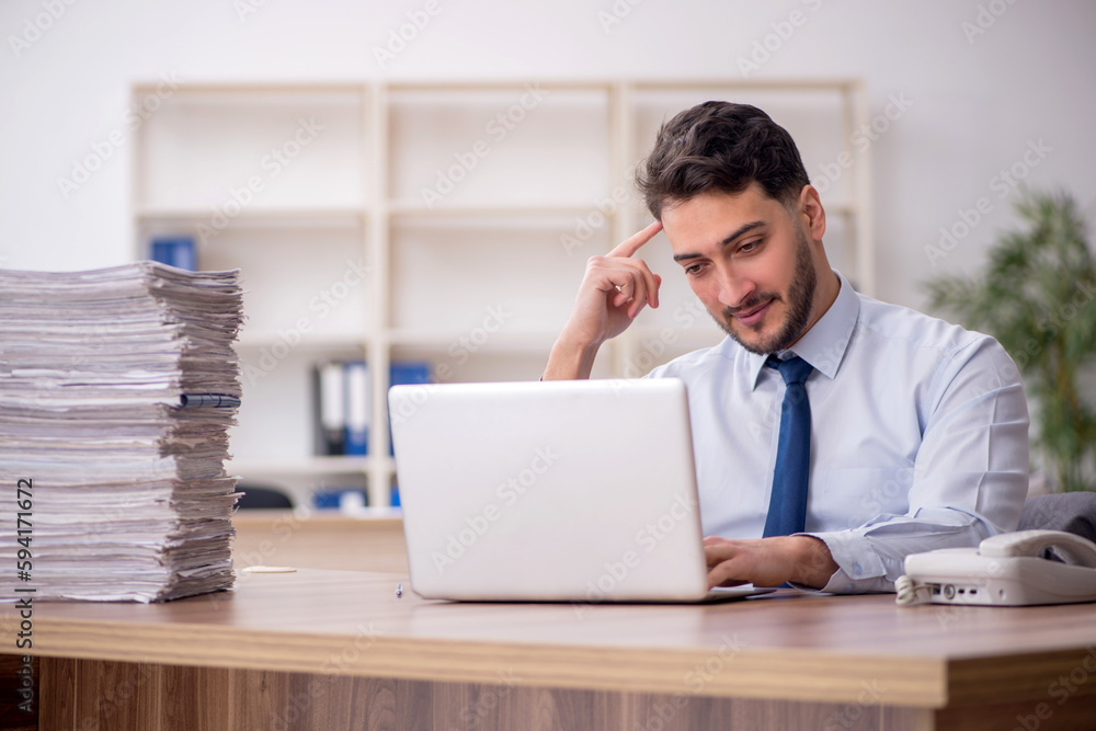 Young male employee and too much work in the office Young male employee and too much work in the office