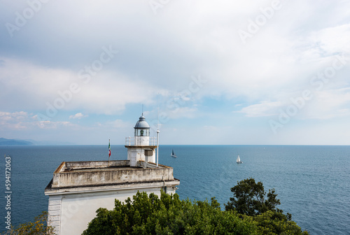 Seascape and old white lighthouse. Port of Portofino village, Genoa province (Genova), Liguria, Italy, Europe. Mediterranean Sea (Ligurian Sea).