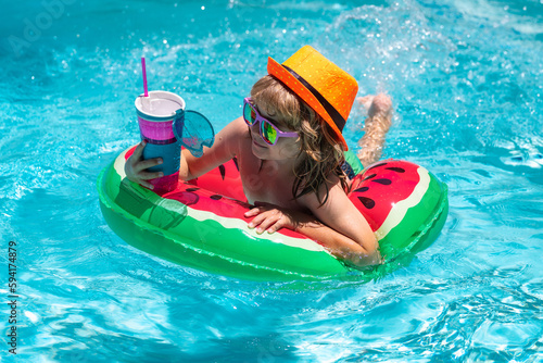 Kids summer vacation  swimming and relax. Happy kid playing with colorful swim ring in swimming pool on summer day. Child water vacation. Children play in tropical resort.