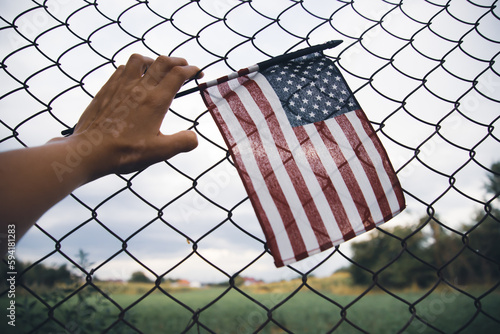 Canvas-taulu Hand holding america flag in front of a barbed fence