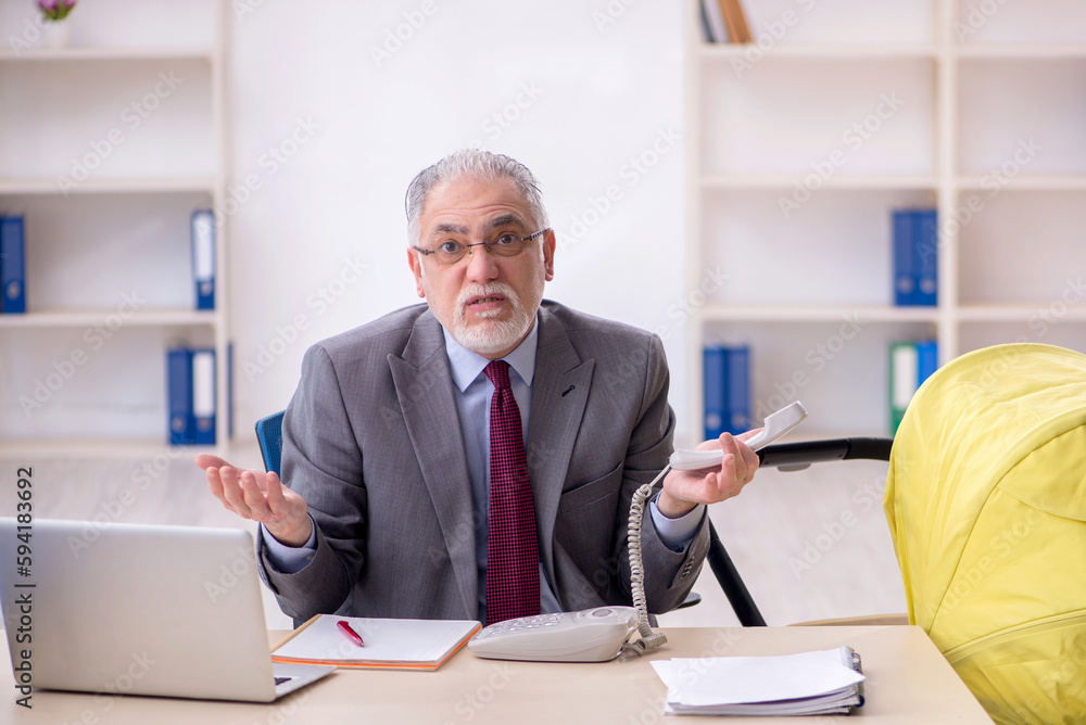 Old male employee looking after new born at workplace Old male employee looking after new born at workplace