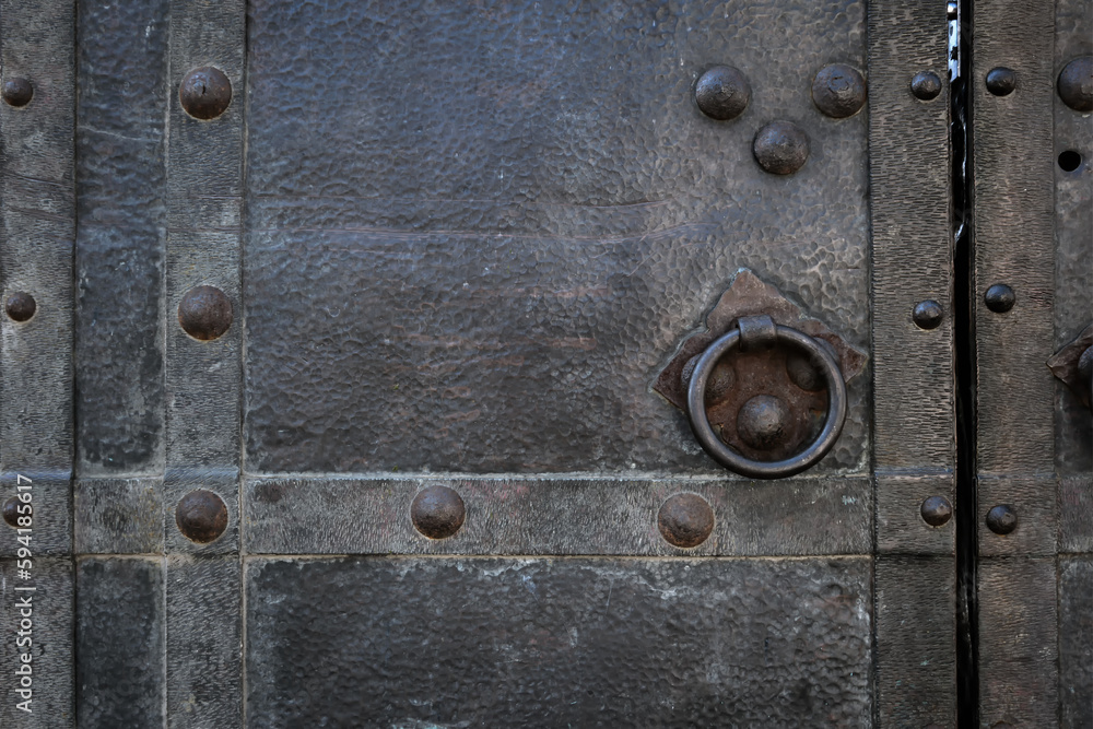 Close-up of an old black iron door with a  handle.
