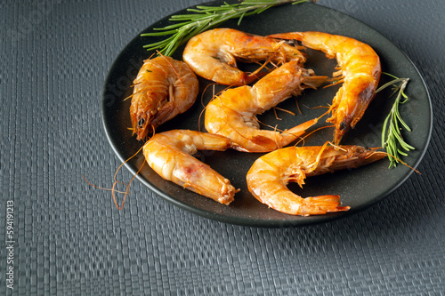 Caridea or boiled shrimps with rosemary in a bowl on a gray table. The idea of delicious dietary seafood for lunch or dinner