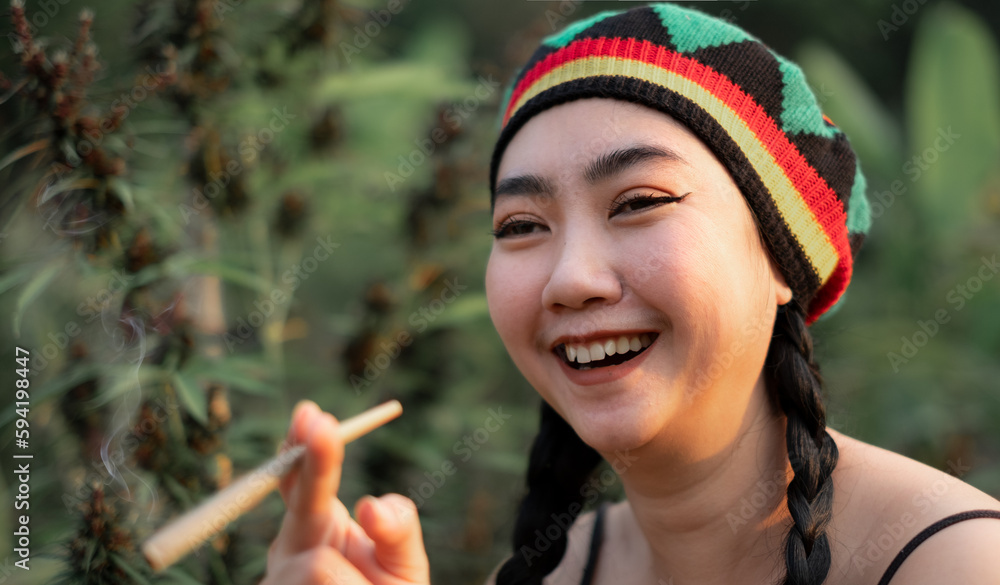 Yong Asia woman smoking marijuana at cannabis tree plant background Yong Asia woman smoking marijuana at cannabis tree plant background