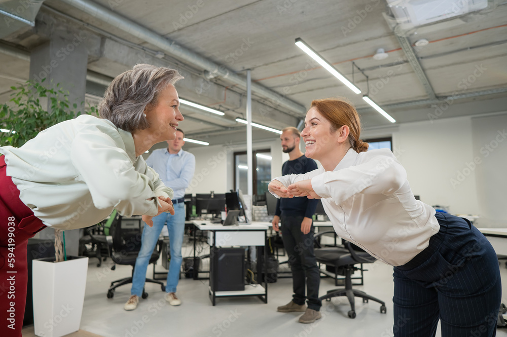 Obraz premium Four office workers warm up during a break. Employees do fitness exercises at the workplace. 