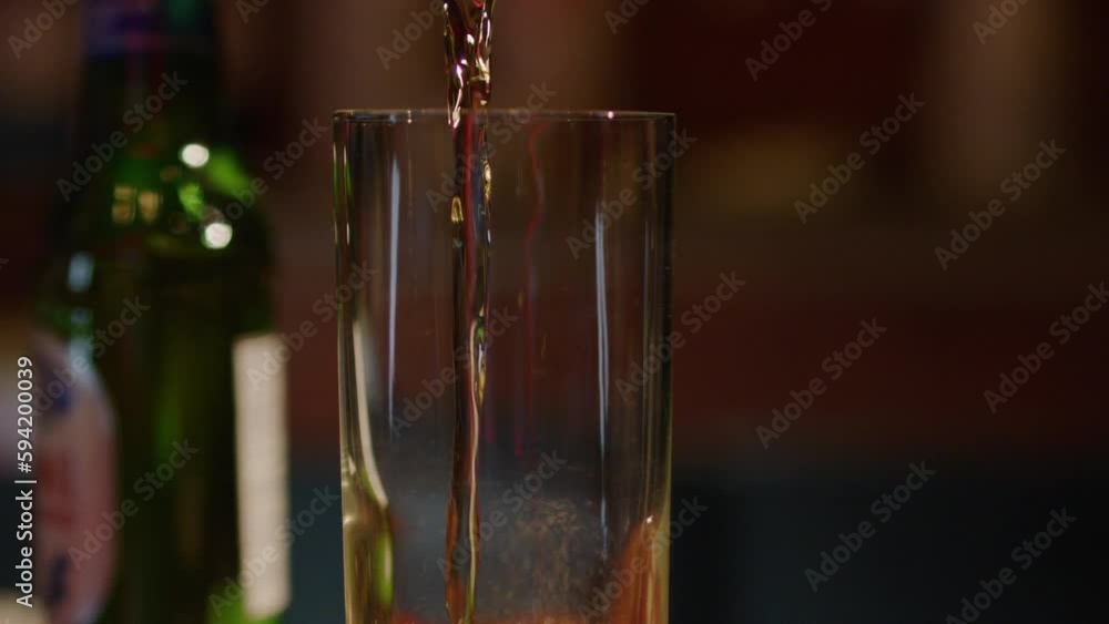 Pouring beer into glass in slowmo and rising foam Pouring beer into glass in slowmo and rising foam