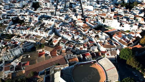 White walled buildings with classic Spanish architecture sit at bottom of green mountain in Ronda