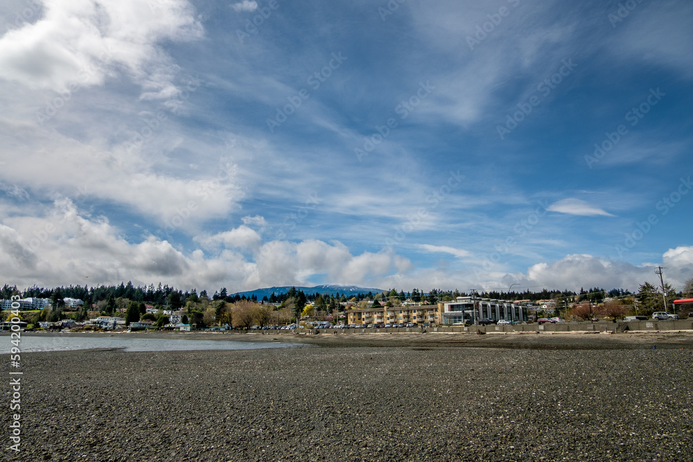 Bare rocks are exposed on Departure Bay Beach at low tide on a sunny day in early springtime. View of the residences along Departure Bay Road, Nanaimo, BC, Canada.