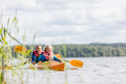 Foto Happy senior active couple kayaking on lake