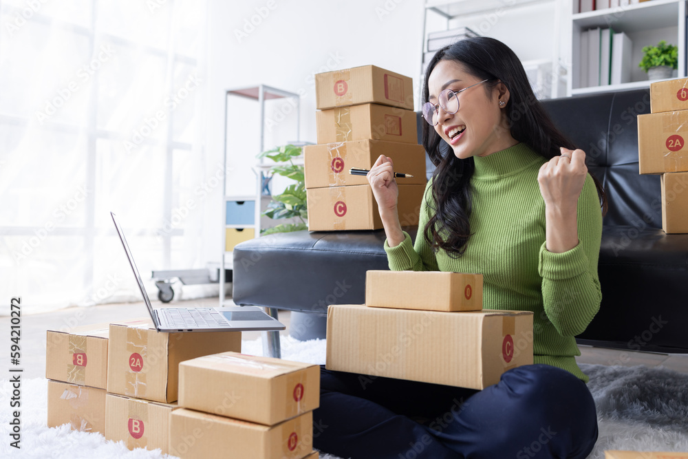 Startup SME small business entrepreneur of freelance Asian woman wearing apron using laptop and box to receive and review orders online to prepare to pack sell to customers, online sme business ideas. Startup SME small business entrepreneur of freelance Asian woman wearing apron using laptop and box to receive and review orders online to prepare to pack sell to customers, online sme business ideas.