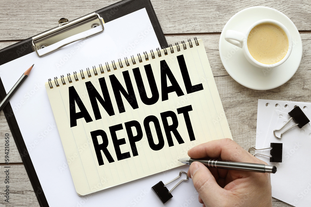 Business Annual Report text on a black folder near a cup of coffee. light wooden background Business Annual Report text on a black folder near a cup of coffee. light wooden background