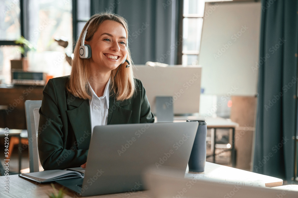 Smiling, using laptop. Young beautiful woman in formal clothes is working in the office Smiling, using laptop. Young beautiful woman in formal clothes is working in the office